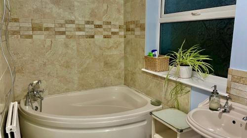 ein Badezimmer mit einer Badewanne und einem Waschbecken in der Unterkunft Magnolia in Peterborough