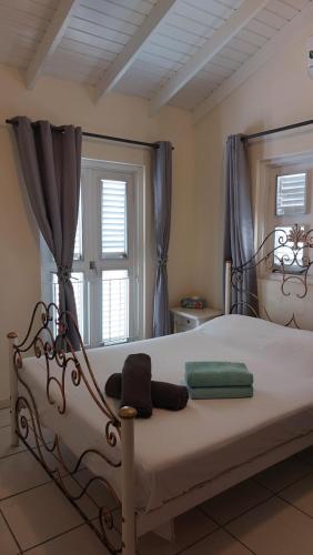 1 dormitorio con cama blanca y cortinas azules en Purple house in colorful city centre, en Willemstad