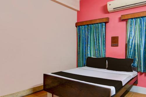 um quarto com uma cama e uma parede rosa em OYO Ramya Guest House em Calcutá