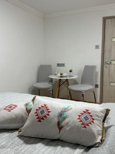 a bed with a pillow on it with a table and chairs at Your Room in Sarajevo