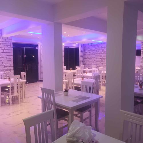 a dining room with white tables and white chairs at Sunny Holiday in Sarandë