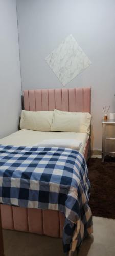 a bed with a blue and white checkered blanket on it at MAMA DELIGHT GUEST ROOM in Abu Dhabi