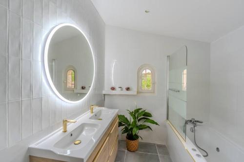 ein weißes Badezimmer mit einem Waschbecken und einem Spiegel in der Unterkunft La Provence : Piscine, Tennis, Cinéma & Plus in Roquefort-les-Pins