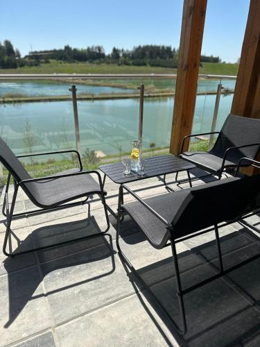 a table and chairs on a porch with a view of the water at Biała Woda in Suwałki