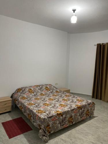 a bed in a white room with a comforter on it at Barbarous in Ajim