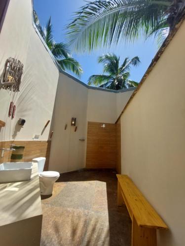 a bathroom with a toilet and a palm tree at Pousada Velho Bateau in Atins
