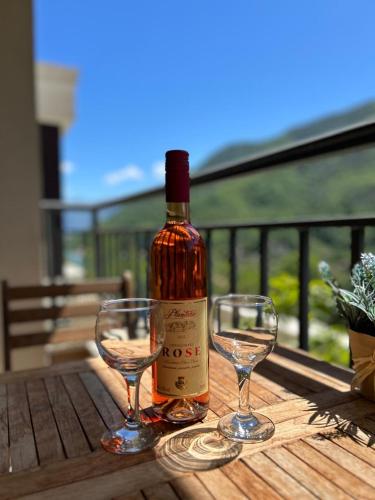 a bottle of wine and two glasses on a wooden table at Pool and spa apartment 1BR in Donji Morinj