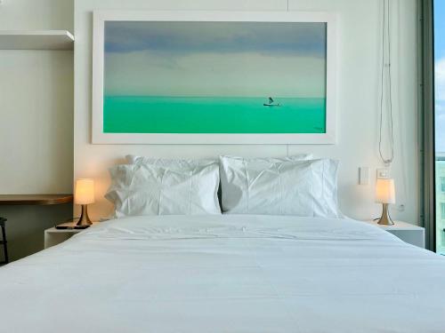 ein Schlafzimmer mit einem weißen Bett mit einem Gemälde darüber in der Unterkunft Wonderful 2BR with impressive view in Cartagena de Indias