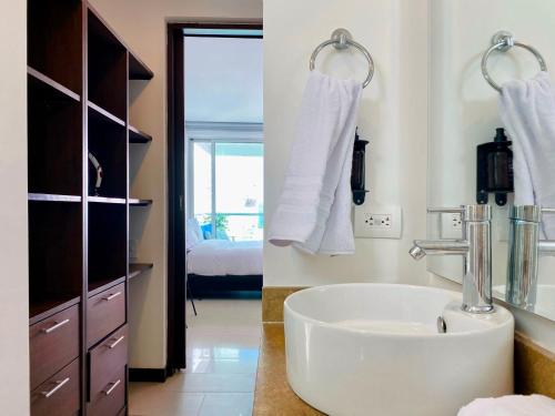 a white bathroom with a sink and a bedroom at Wonderful 2BR with impressive view in Cartagena de Indias
