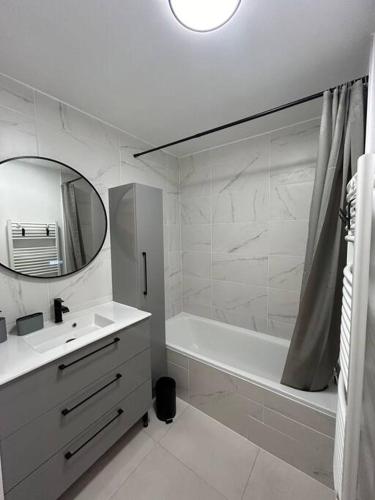 La salle de bains blanche est pourvue d'une baignoire, d'un lavabo et d'un miroir. dans l'établissement T2 cosy avec parking, à Annemasse