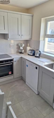 a kitchen with white cabinets and a sink at Lios na Mara Lahinch in Lahinch