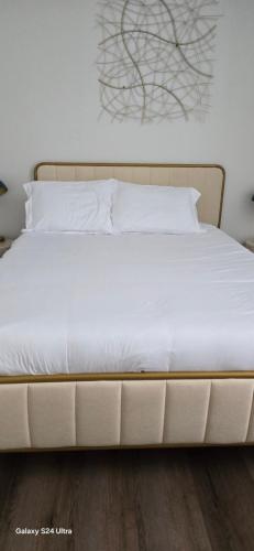 een groot wit bed met witte lakens en kussens bij apartment in Los Angeles