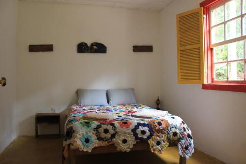 Chalé na floresta com frigobar في أورو بريتو: غرفة نوم مع سرير ولحاف ملون عليها