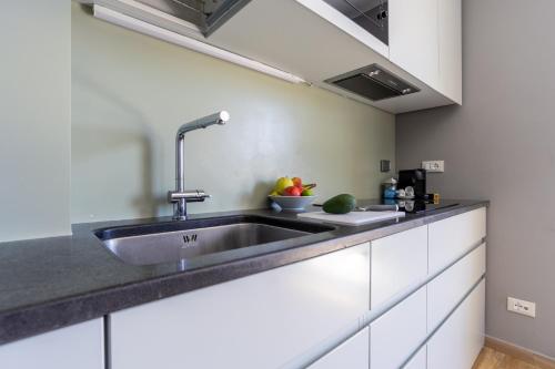 a kitchen with a sink and a bowl of fruit on the counter at SUITE Home Ladispoli in Ladispoli
