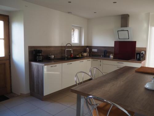 une cuisine avec des armoires blanches et une table en bois dans l'établissement La Picane, à Gagnac-sur-Cère