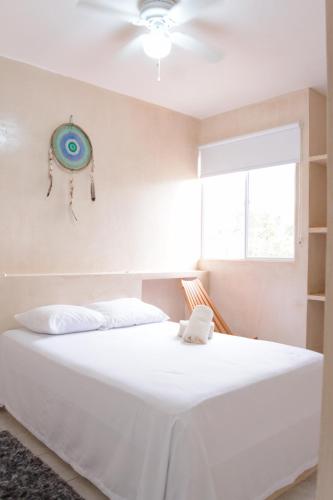 a white bed in a room with a ceiling fan at Kin Tulum Apartamentos in Tulum