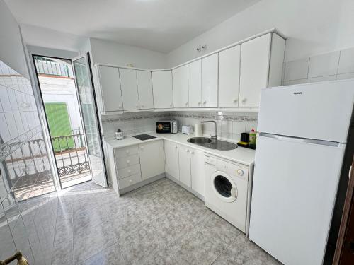 a white kitchen with a sink and a refrigerator at Cabildo 3 in Sanlúcar de Barrameda