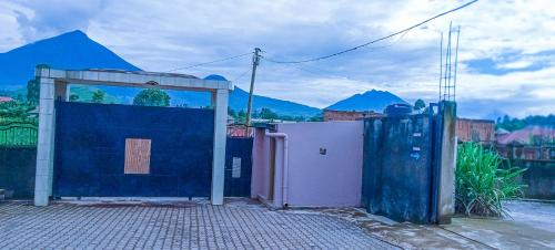 a gate to a building with mountains in the background at Mianzi Guest House in Kisoro