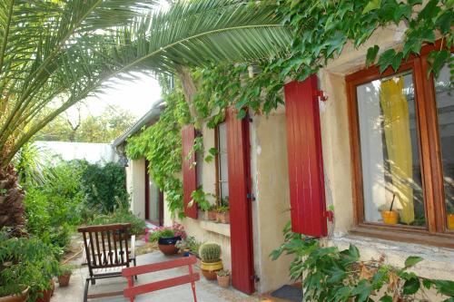 une maison avec des portes rouges, un banc et des plantes dans l'établissement Chambre donnant sur jardin, à Nîmes