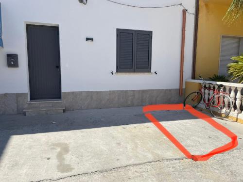 una manguera roja en el suelo frente a un edificio en Testa di Moro, en Marsala