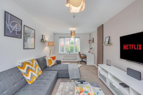 a living room with a gray couch and a tv at Oakbridge House - 6 mins drive to CMK - Free Parking, Fast WiFi, Smart TVs with Sky and Netflix by Yoko Property in Milton Keynes