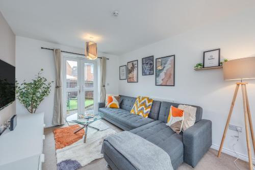 a living room with a blue couch and a window at Oakbridge House - 6 mins drive to CMK - Free Parking, Fast WiFi, Smart TVs with Sky and Netflix by Yoko Property in Milton Keynes