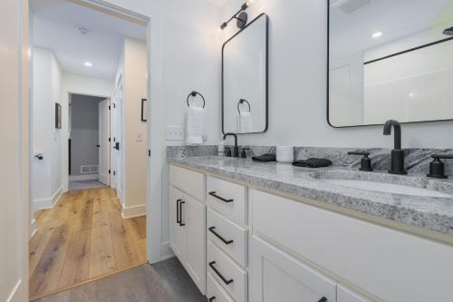 a white bathroom with two sinks and a mirror at Bonjour Soha- pool- close to beach in South Haven