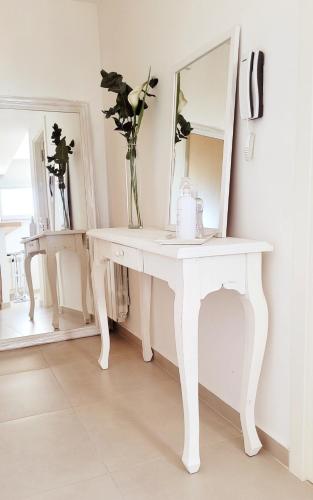 a white dressing table with a vase of flowers on it at Cala in Olavarría