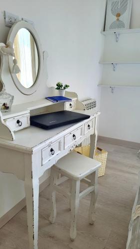 a white dressing table with a mirror and a stool at Cala in Olavarría