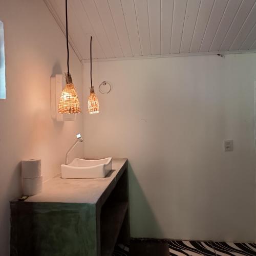 a bathroom with a sink and two lights at Pousada Pedra do Negro in Caraíva
