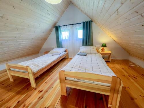 two beds in a room with a attic at Domek Życiny nad Zalewem Chańcza in Życiny