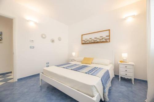 a white bedroom with a bed and a night stand at Belvedere Apartments A in Marina di Mancaversa