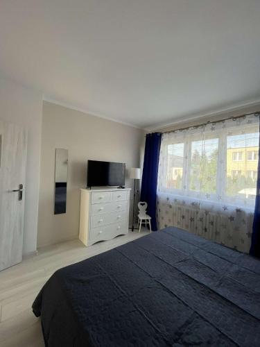 a bedroom with a bed and a dresser and a window at Apartament nad jeziorem Ukiel in Olsztyn