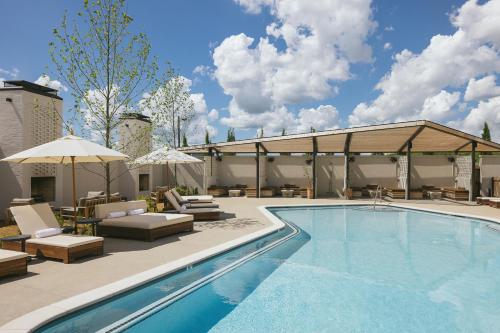a swimming pool with chairs and umbrellas next to a building at Drift Nashville in Nashville