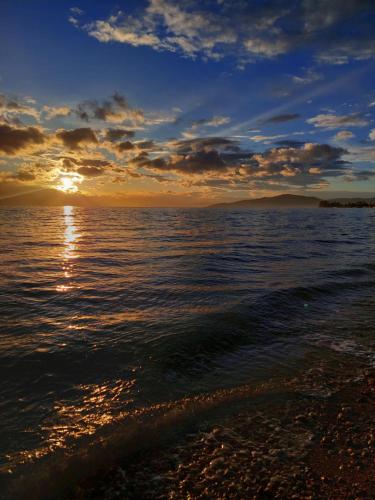 a sunset over the ocean with the sun setting at Platanidia Apartment Pelion in Platanidia