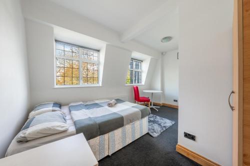 1 dormitorio con 1 cama y 1 silla roja en Barnet Serviced Accommodation - Elegant 5-Bedroom Home, Just a 7-Minute Stroll from High Barnet Station - Book Your Stay Today!", en New Barnet