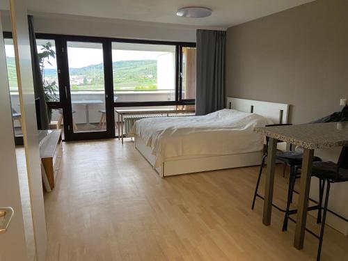 a bedroom with a bed and a table and a balcony at Freshly renovated Studio apartment - top location in Weinstadt in Weinstadt