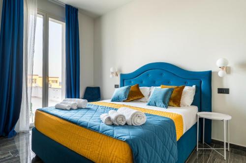 sypialnia z niebieskim łóżkiem i ręcznikami w obiekcie Fiko Suite w mieście Roccella Ionica