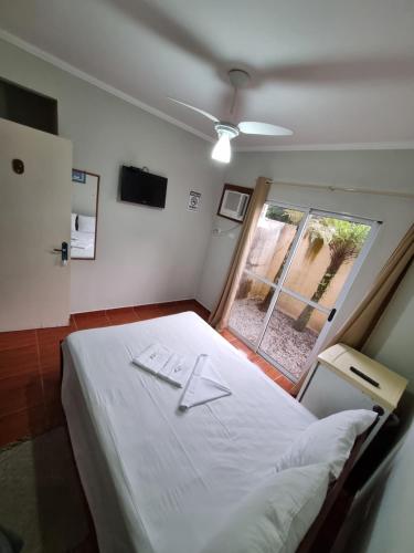 a bedroom with a large white bed with a window at Camping Pousada Ilha do Mel - Frente ao Mar in Boracéia