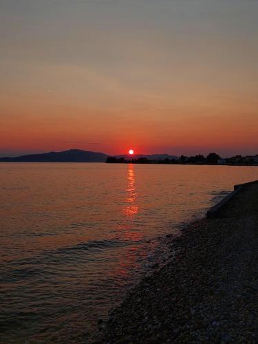 a sunset over a body of water with the sun setting at Platanidia Apartment Pelion in Platanidia