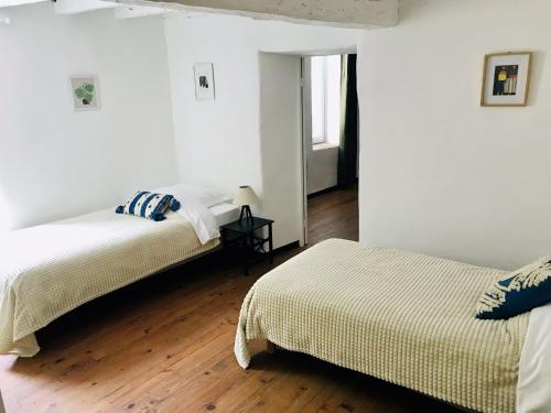two beds in a white room with wooden floors at Gîte des Canelles in Villespy