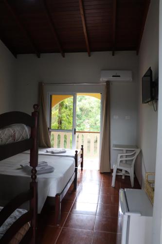 a bedroom with a bed and a large window at Camping Pousada Ilha do Mel - Frente ao Mar in Boracéia