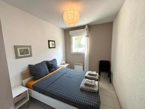 une chambre avec un lit avec des oreillers bleus et une fenêtre dans l'établissement Maison de la Plage N°4, au Grau-dʼAgde
