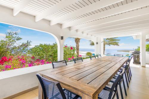 ein Esszimmer mit einem Holztisch und Stühlen in der Unterkunft Exclusive 10-Guest Seaview Villa in Gated Community with Pool & Private Beach Access in Willibrordus