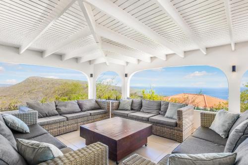 ein Wohnzimmer mit Sofas und einem Tisch in der Unterkunft Exclusive 10-Guest Seaview Villa in Gated Community with Pool & Private Beach Access in Willibrordus