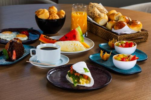 a table with plates of food and a cup of coffee at Novotel RJ Praia de Botafogo in Rio de Janeiro