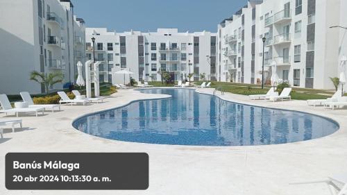 una piscina con sillas y edificios blancos en Departamento Acapulco Diamante - 2 habitaciones, en Acapulco