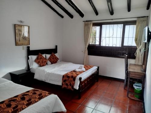 a bedroom with two beds and a window at Hotel MAXIRUMA - Villa TAMAUKA in Iza