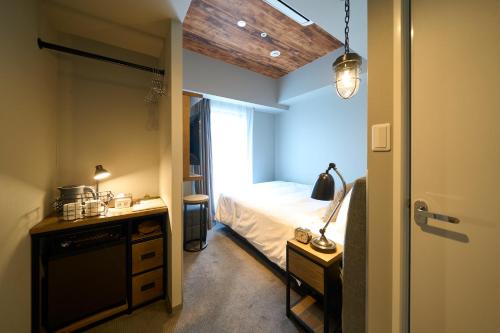 a bedroom with a bed and a desk with a lamp at Hotel Resol Akihabara in Tokyo