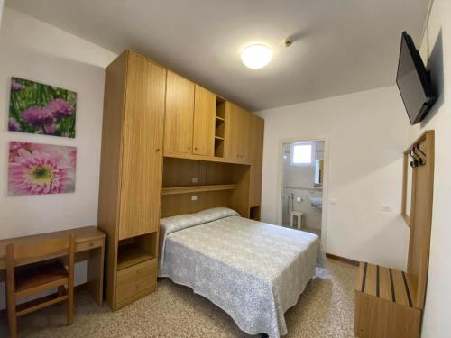 a bedroom with a bed and a wooden cabinet at Hotel Erika in Caorle